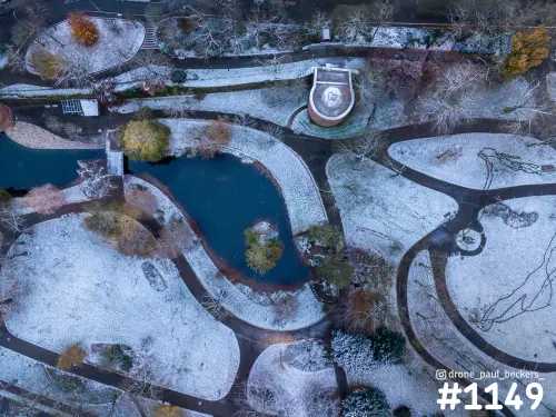 Luchtfoto van het Kronenburgerpark in Nijmegen onder een laagje sneeuw, met slingerende paden en een donkere vijver