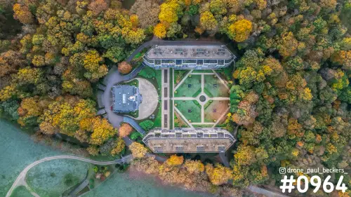 Luchtfoto recht van boven op een landhuis met symmetrische tuin, omringd door bos in gele en oranje herfstkleuren