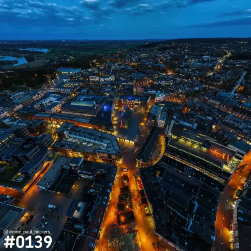 Luchtfoto van de Marienburg kapel in Nijmegen in het blauwe uur, met verlichte straten en daken van de binnenstad