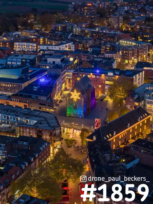 Luchtfoto van de Marienburg kapel in het centrum van Nijmegen, kleurrijk verlicht met een lichtster op de gevel in de avond