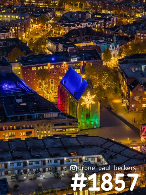 Luchtfoto van de Marienburg kapel in Nijmegen 's avonds, blauw en kleurig verlicht met een lichtsneeuwvlok op de gevel