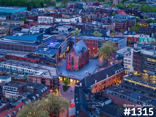 Luchtfoto van de Marienburg kapel in Nijmegen bij schemering, paars verlicht op een plein tussen bakstenen panden