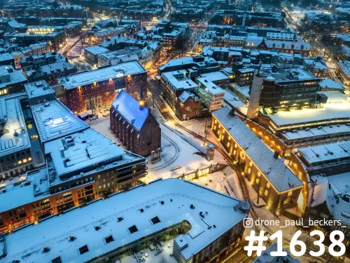 Luchtfoto van de Marienburg kapel in het centrum van Nijmegen in de blauwe schemering, met sneeuw op de daken en verlichte gevels