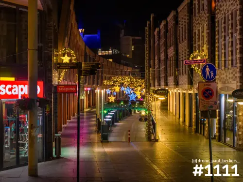 Marikenstraat in Nijmegen in de avond met kerstverlichting boven de lege winkelstraat en lichtreflecties op de bestrating