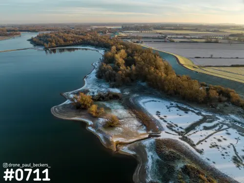 Luchtfoto van de Millingerwaard bij Kekerdom in de winter, met rijp en sneeuw langs een stille rivierplas en gouden bomen