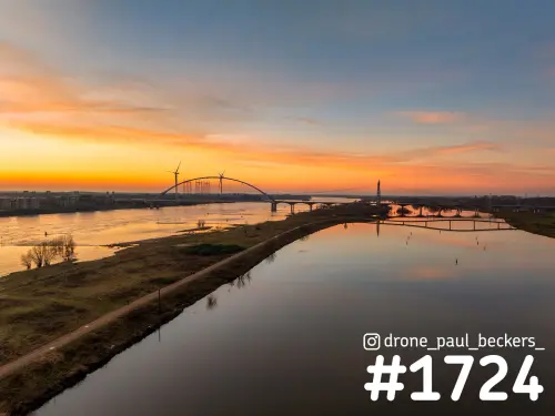 Luchtfoto van de nevengeul en De Oversteek in Nijmegen, met oranje zonsondergang die weerspiegelt in het stille water