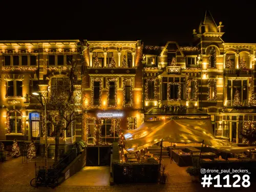 Luchtfoto van Brasserie Manna in Nijmegen met kerstverlichting op de gevels en een verlicht terras onder een tent
