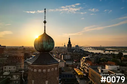 Luchtfoto van Nijmegen-centrum bij laagstaande zon: groene koepeltoren, Stevenskerk en de Oversteek over de Waal