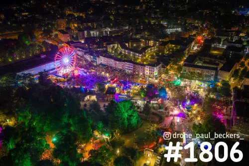 Luchtfoto van de Vierdaagsefeesten in het centrum van Nijmegen bij nacht, met reuzenrad en kleurrijk verlichte bomen