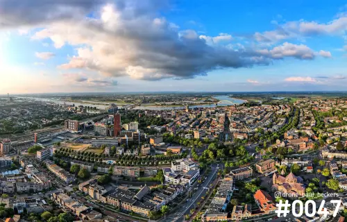 Luchtfoto van Nijmegen met Keizer Karel Plein en de Waal aan de horizon, onder dramatische wolken bij laagstaande zon