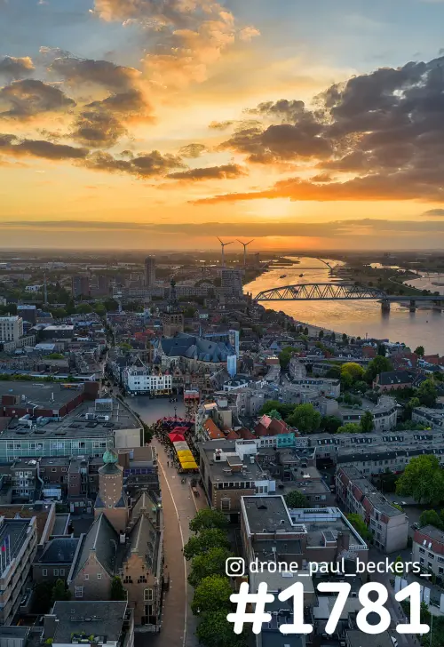 Luchtfoto van het centrum van Nijmegen bij zonsondergang met de Stevenskerk, de Waal en een stalen boogbrug