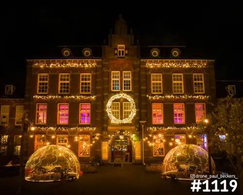 Historisch bakstenen gebouw in Nijmegen in de avond met kerstverlichting, roze verlichte ramen en twee iglotenten