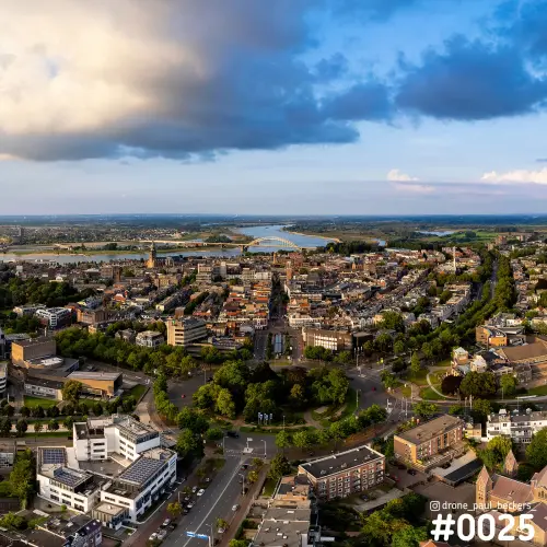 Luchtfoto van Nijmegen met Keizer Karel Plein, Stevenskerk en de Waalbrug, onder een donkere wolkenlucht in het avondlicht