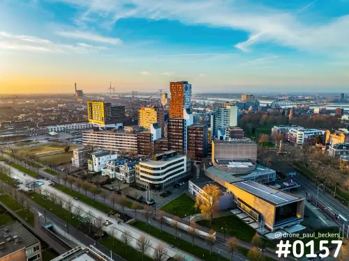 Luchtfoto van Nijmegen met Nimbus en de Waal in de verte, hoogbouw met oranjebruine gevel in de laagstaande zon