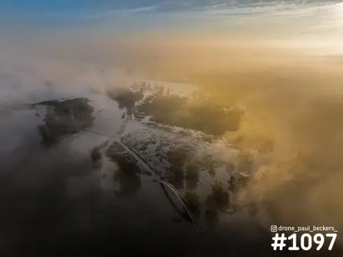 Luchtfoto van de Ooijpolder bij Nijmegen met laaghangende mist en gouden zonlicht boven overstroomde uiterwaarden
