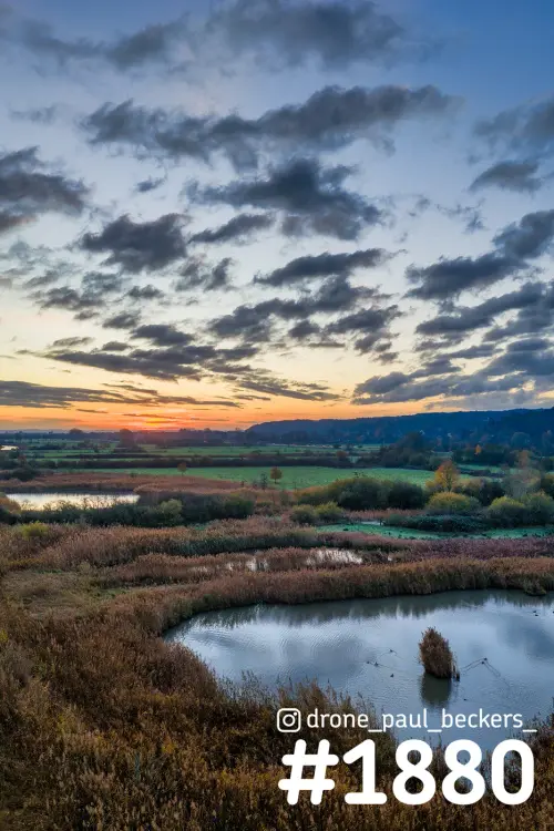Luchtfoto van de Ooijpolder bij Nijmegen in de herfst, met rietkragen en een plas onder een avondlucht vol donkere wolken