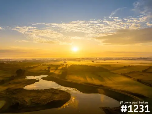 Luchtfoto van de Ooijpolder bij Nijmegen met zonsopkomst, mist boven weilanden en zon weerspiegeld in een waterbocht