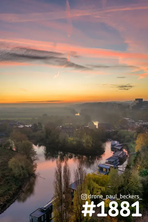 Luchtfoto van een rivierbocht in de Ooijpolder in de herfst, met woonboten, laaghangende mist en een roze-oranje lucht