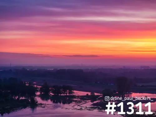 Luchtfoto van de Ooijpolder bij Nijmegen met roze en oranje zonsopkomst boven overstroomde uiterwaarden en lichte mist