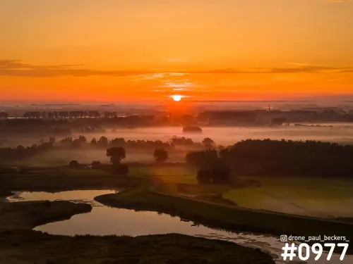 Luchtfoto van de Ooijpolder bij zonsopkomst met mist boven weilanden en een plas met weerspiegeling