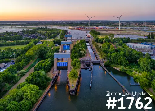 Luchtfoto van de sluizen bij Weurt in de schemering, met kanaal, windturbines en haventerrein op de achtergrond