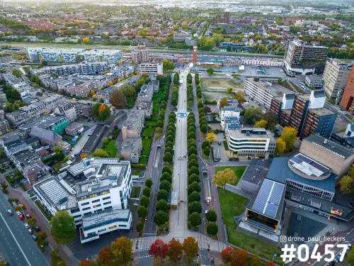 Luchtfoto van het Stationsgebied in Nijmegen in de herfst, met een bomenlaan die naar het spoor en een rode toren leidt