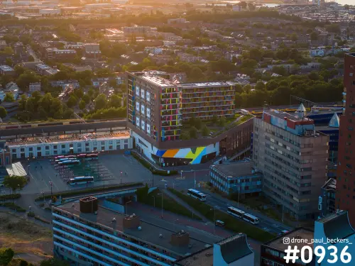 Luchtfoto van het stationsgebied in Nijmegen: kleurrijk flatgebouw en busstation in het warme licht van de laagstaande zon