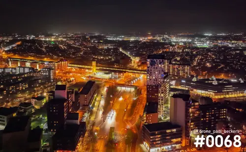 Luchtfoto van het stationsgebied in Nijmegen bij nacht, met verlichte hoogbouw en een drukke weg vol autolichten