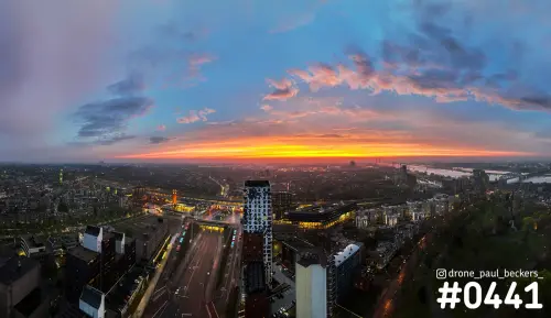 Luchtfoto van het Stationsgebied in Nijmegen bij zonsondergang, met de hoogbouw van Nimbus en de Waal aan de horizon