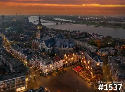 Luchtfoto van de Stevenskerk en Grote Markt in Nijmegen bij avondrood, met sterverlichting op de gevels