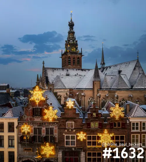 Luchtfoto van de Stevenskerk aan de Grote Markt in Nijmegen in het blauwe uur, met sneeuw op het dak en lichtgevende sneeuwvlokken