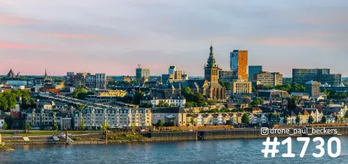 Panorama van Nijmegen vanaf de Waal in avondlicht, met de Stevenskerk en de huizen langs de Handelskade