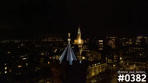 Nijmegen bij nacht met de verlichte toren van de Stevenskerk en een glinsterende torenspits bij het Kronenburgerpark