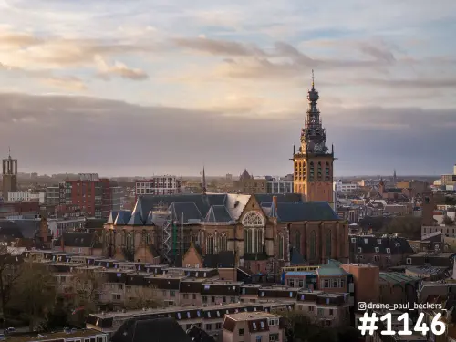 Luchtfoto van de Stevenskerk in het centrum van Nijmegen bij avondlicht, met steiger op het dak en wolken erboven