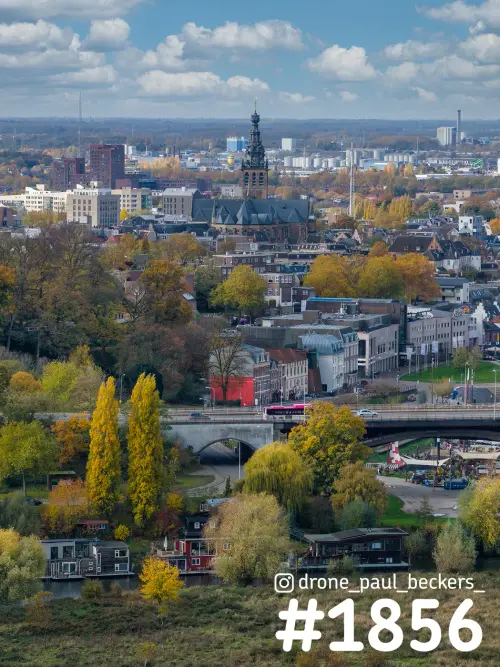 Luchtfoto van de Stevenskerk en het centrum van Nijmegen in de herfst, met gele bomen en woonboten langs de Waal