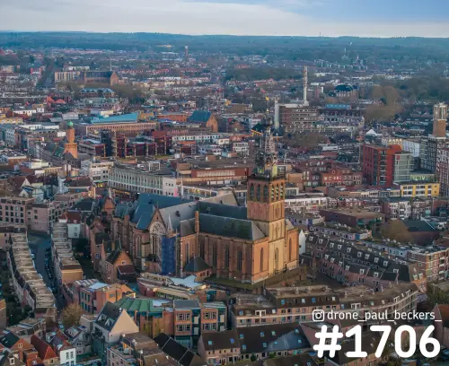 Luchtfoto van de Stevenskerk in het centrum van Nijmegen, met steiger tegen de zijkant en lage zon op de toren