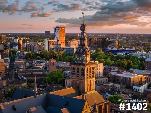 Luchtfoto van de Stevenskerk in het centrum van Nijmegen bij zonsondergang, met de toren in warm licht en daken eromheen