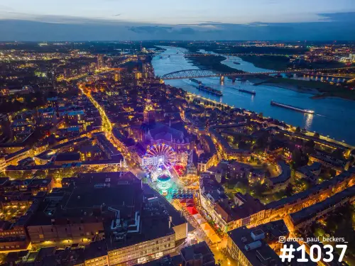 Luchtfoto van de Nijmeegse binnenstad in de avond met kermis en reuzenrad bij de Stevenskerk, de Waal en De Oversteek