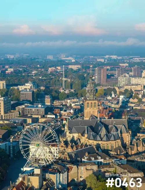 Luchtfoto van de Stevenskerk in Nijmegen met het reuzenrad van de kermis, in laag zonlicht boven de daken