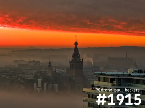 Luchtfoto van de Stevenskerk in Nijmegen in de mist, met rood-oranje lucht en een flatgebouw aan de Handelskade