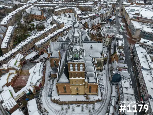 Luchtfoto van de Stevenskerk in het centrum van Nijmegen met sneeuw op de daken en sporen rond de kerk