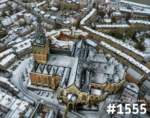 Luchtfoto van de Stevenskerk in het centrum van Nijmegen in de sneeuw, met besneeuwde daken en de toren links