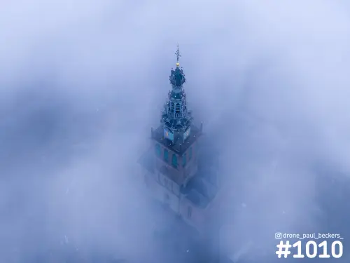 Luchtfoto van de Stevenskerk in Nijmegen, de toren met klokken en spits omringd door dikke blauwe mist