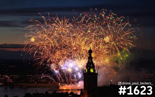 Oranje vuurwerk boven Nijmegen met de toren van de Stevenskerk als silhouet in de avondschemering tijdens de Vierdaagse