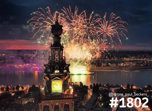 Luchtfoto van de Stevenskerk in Nijmegen met vuurwerk boven de Waal, avondrood aan de horizon en Lent op de oever