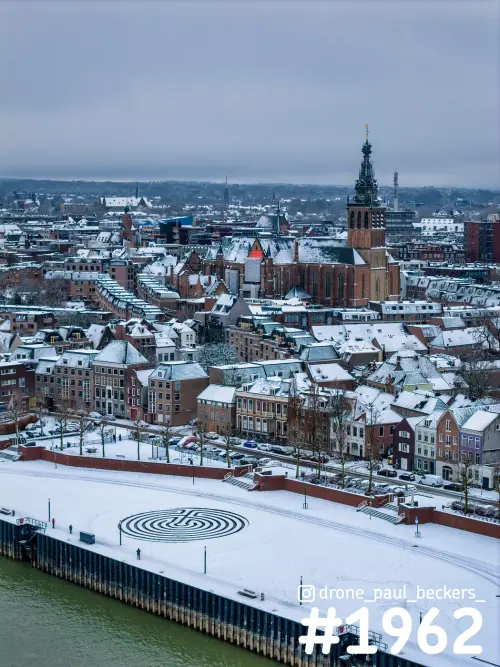 Luchtfoto van de Stevenskerk en het centrum van Nijmegen onder sneeuw, met de Waalkade en het labyrint aan de Waal