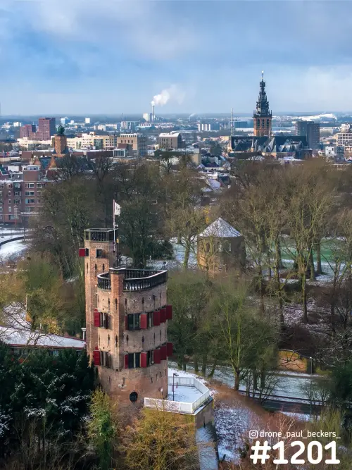 Luchtfoto van een bakstenen toren met rode luiken in het Valkhofgebied, met de Stevenskerk en sneeuw in Nijmegen