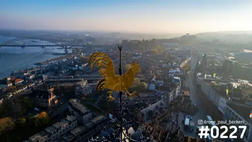 Luchtfoto van de gouden windhaan op de Stevenskerk in Nijmegen, met de Waal en Waalbrug in de ochtendmist