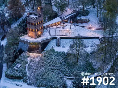 Luchtfoto van de Belvedere-toren in het Valkhof gebied in Nijmegen, met sneeuw en verlichte ramen in het blauwe uur