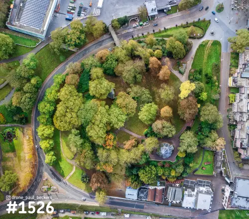 Luchtfoto recht van boven van het Valkhof gebied in Nijmegen, herfstbomen rond een glazen koepel en een gebogen weg